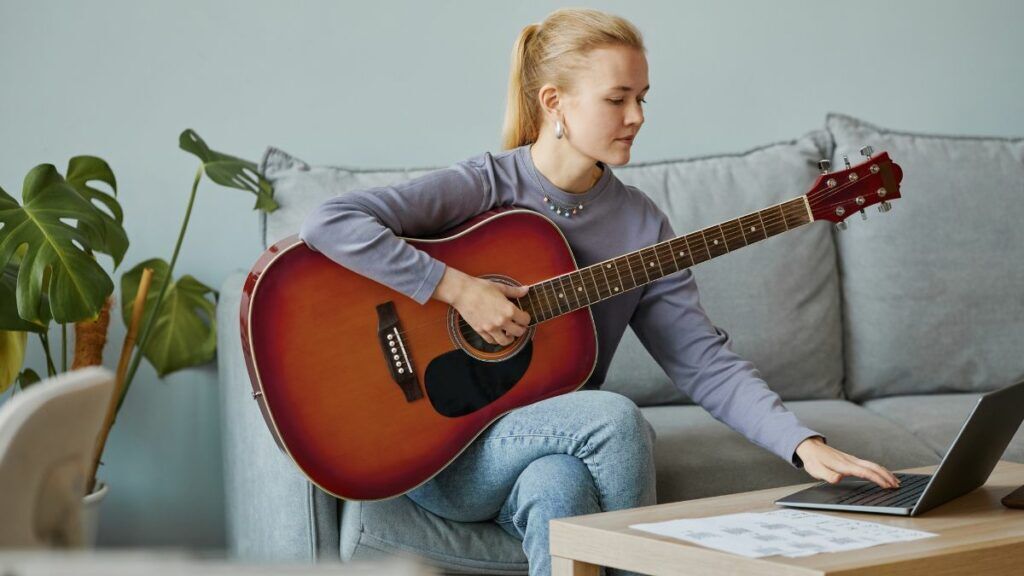 fille apprend guitare seule Une fille qui apprend la guitare seule avec son ordinateur